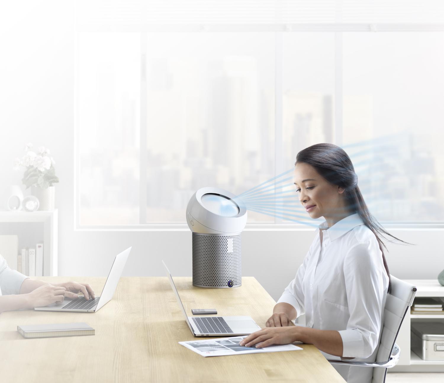 An office worker using a Dyson Pure Cool Me personal purifier fan