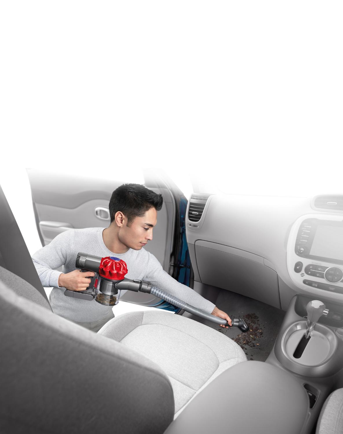 Homme utilisant une rallonge de tuyau pour nettoyer le plancher de sa voiture.