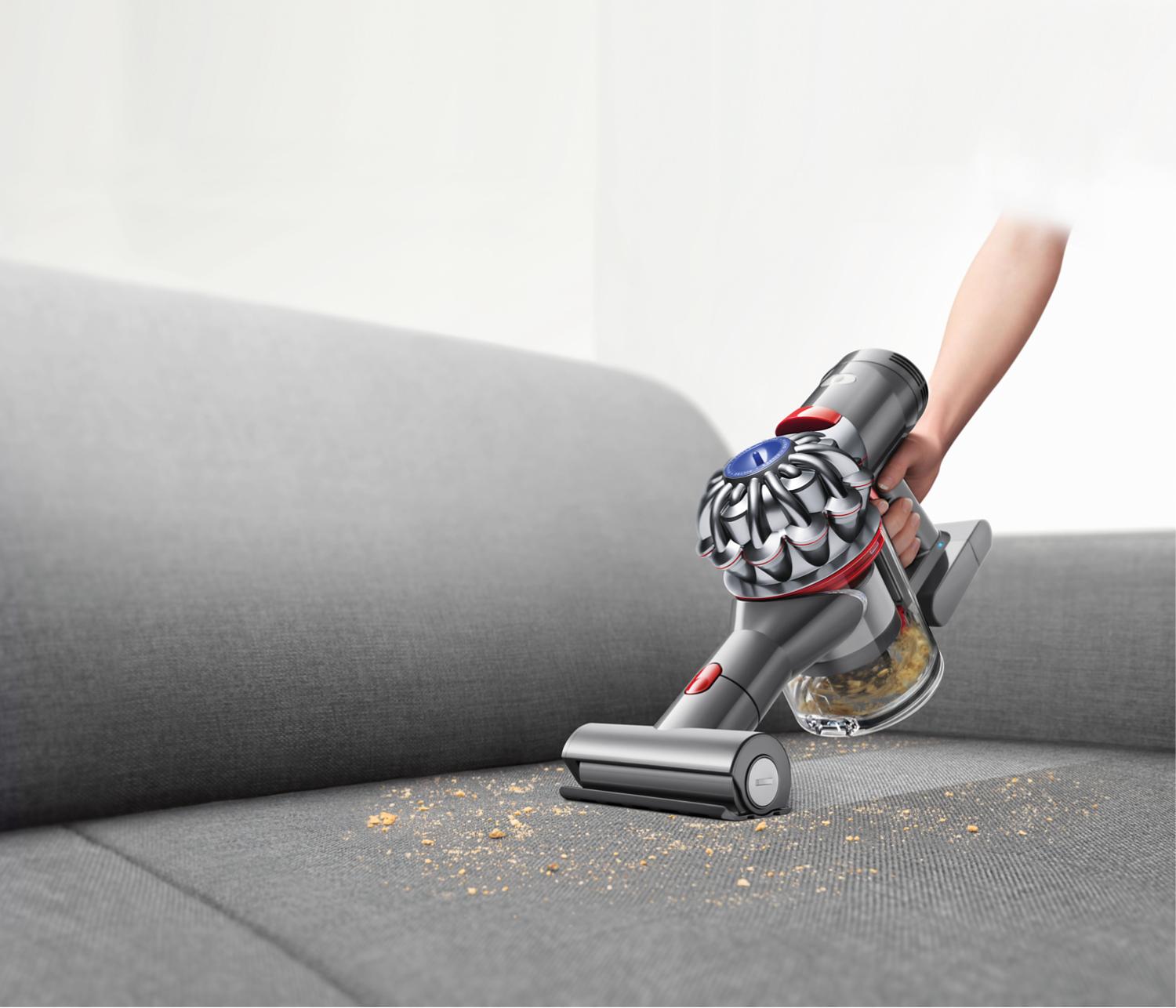 Dyson handheld vacuum being used on sofa