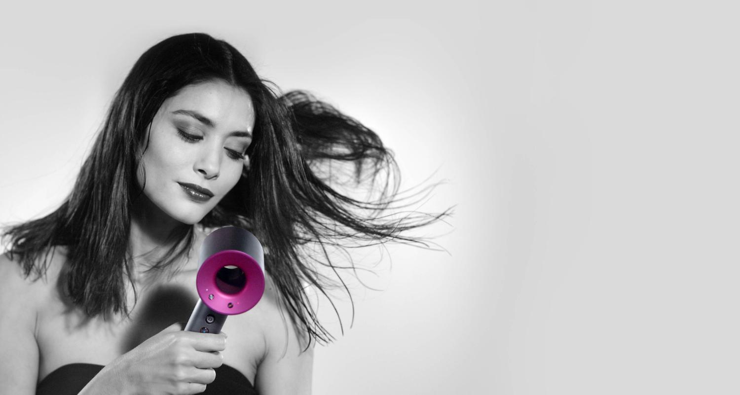 Woman drying hair with Dyson Supersonic Iron Fuchsia