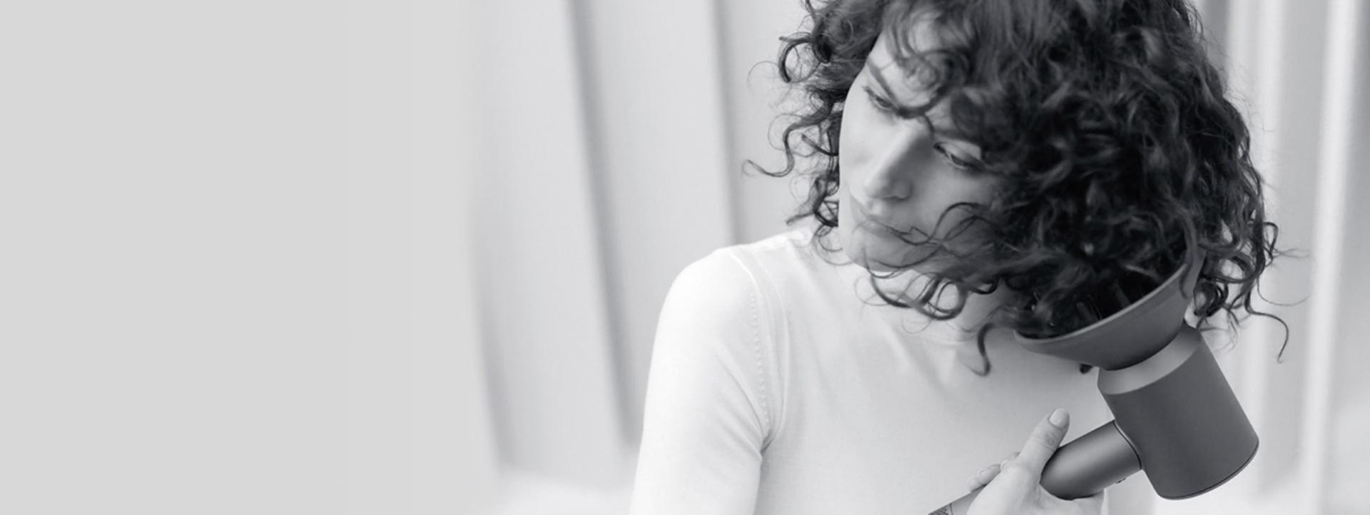 Woman drying her hair with the Dyson Supersonic hair dryer with diffuser attachment