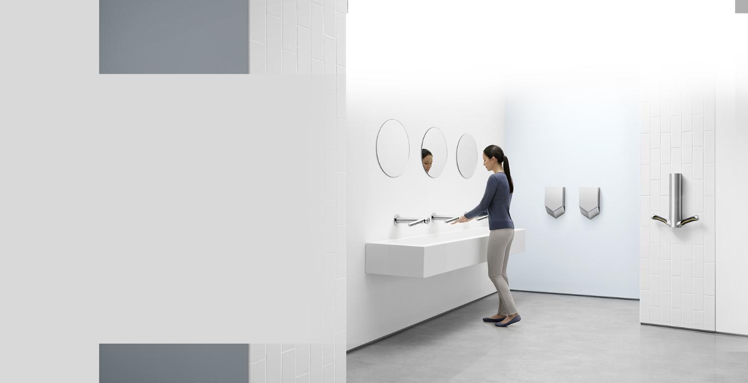 Woman in a bathroom surrounded by different Dyson Airblade machines.
