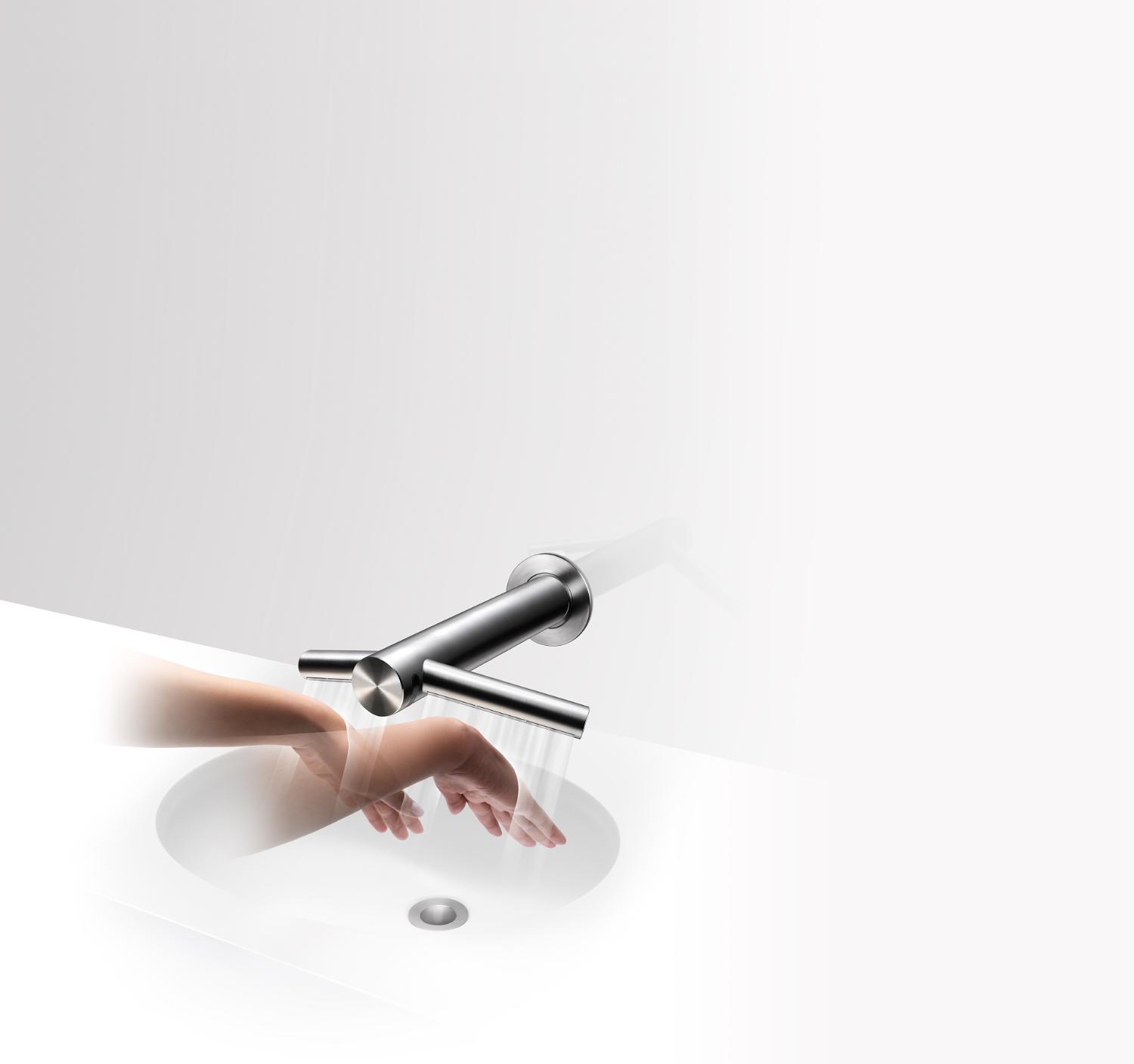 Dyson airblade tap mounted to wall. Demonstrating drying hands