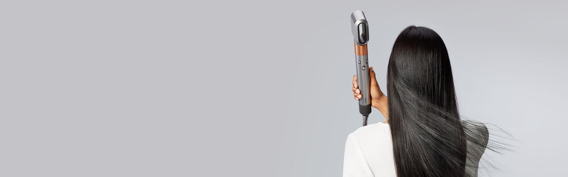 Model blow dries her hair with the Dyson Airwrap multi-styler and dryer.