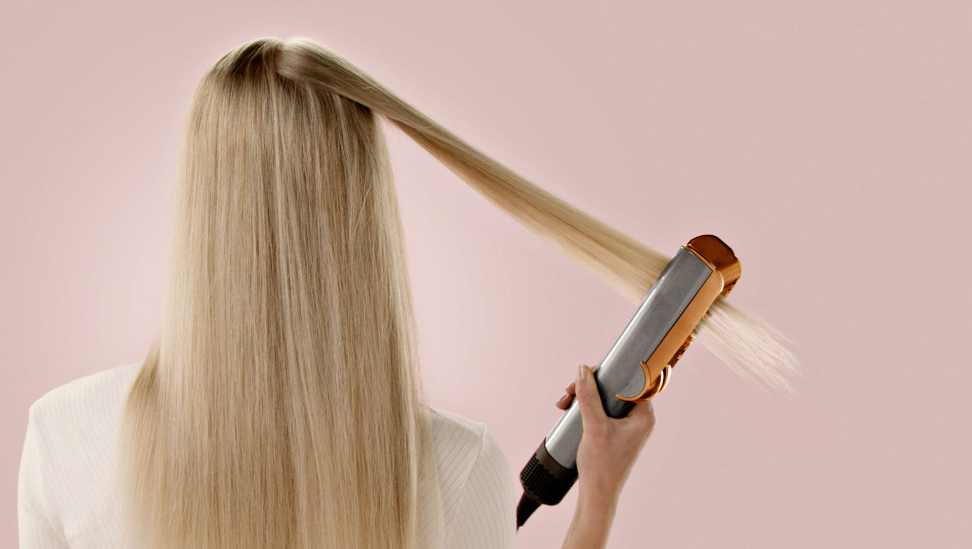 Una modelo usa la Dyson Airstrait para alisar un mechón de cabello.