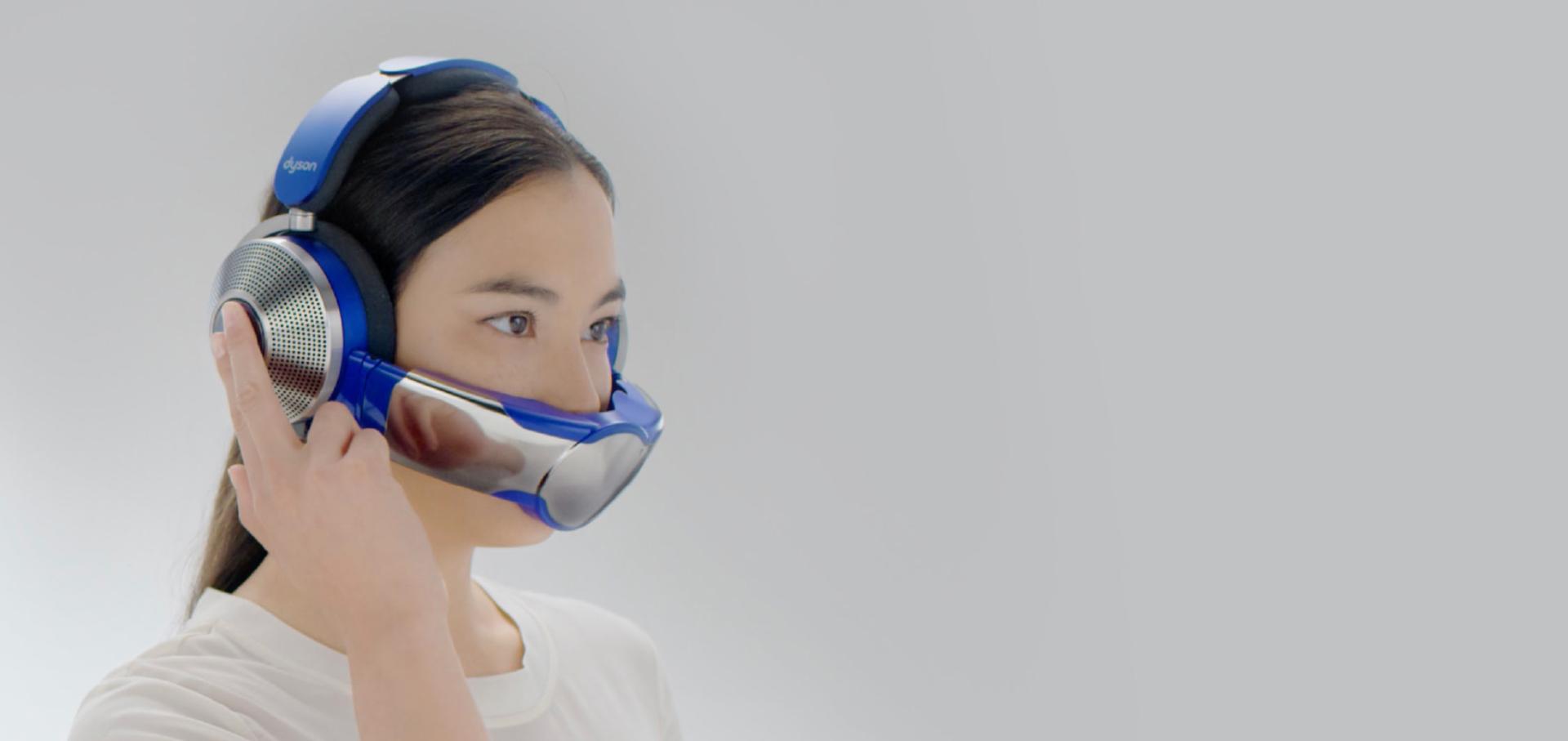 Hava temizleme özellikli Dyson Zone kulaklığın ANC modlarını değiştirmek için kulaklığın yan tarafına dokunan bir kadın.