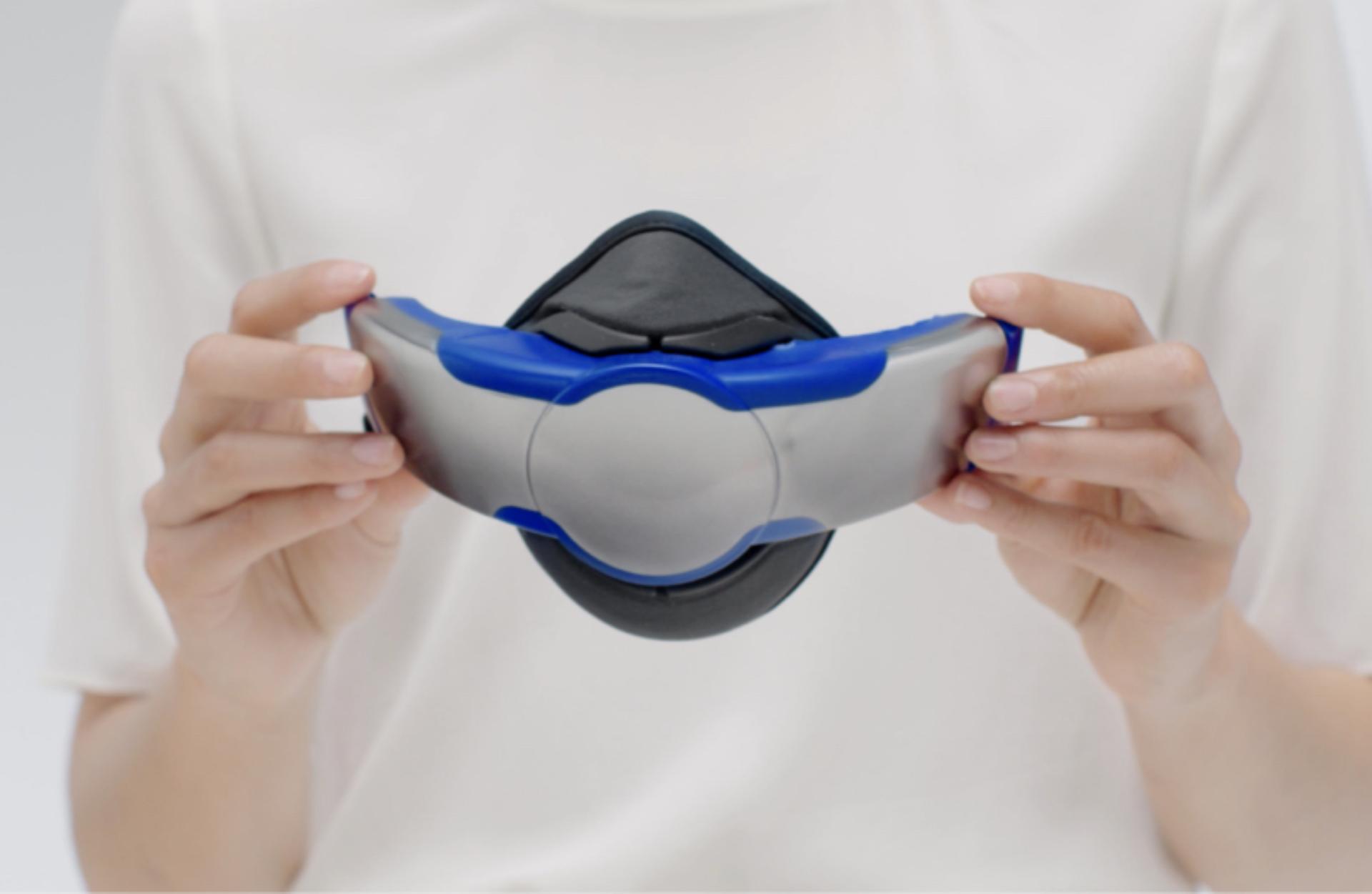 A woman holds the visor with the Community face covering attached.