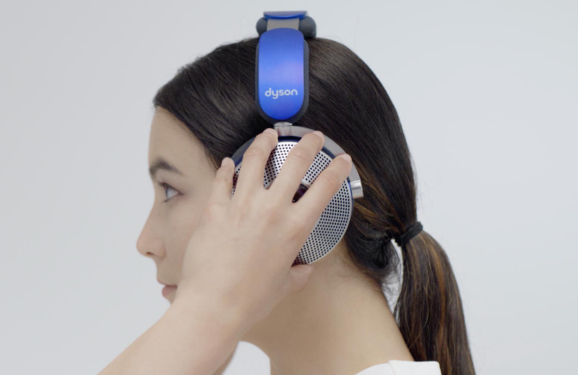 Side view of a woman adjusting the Dyson Zone air-purifying headphones on her head.