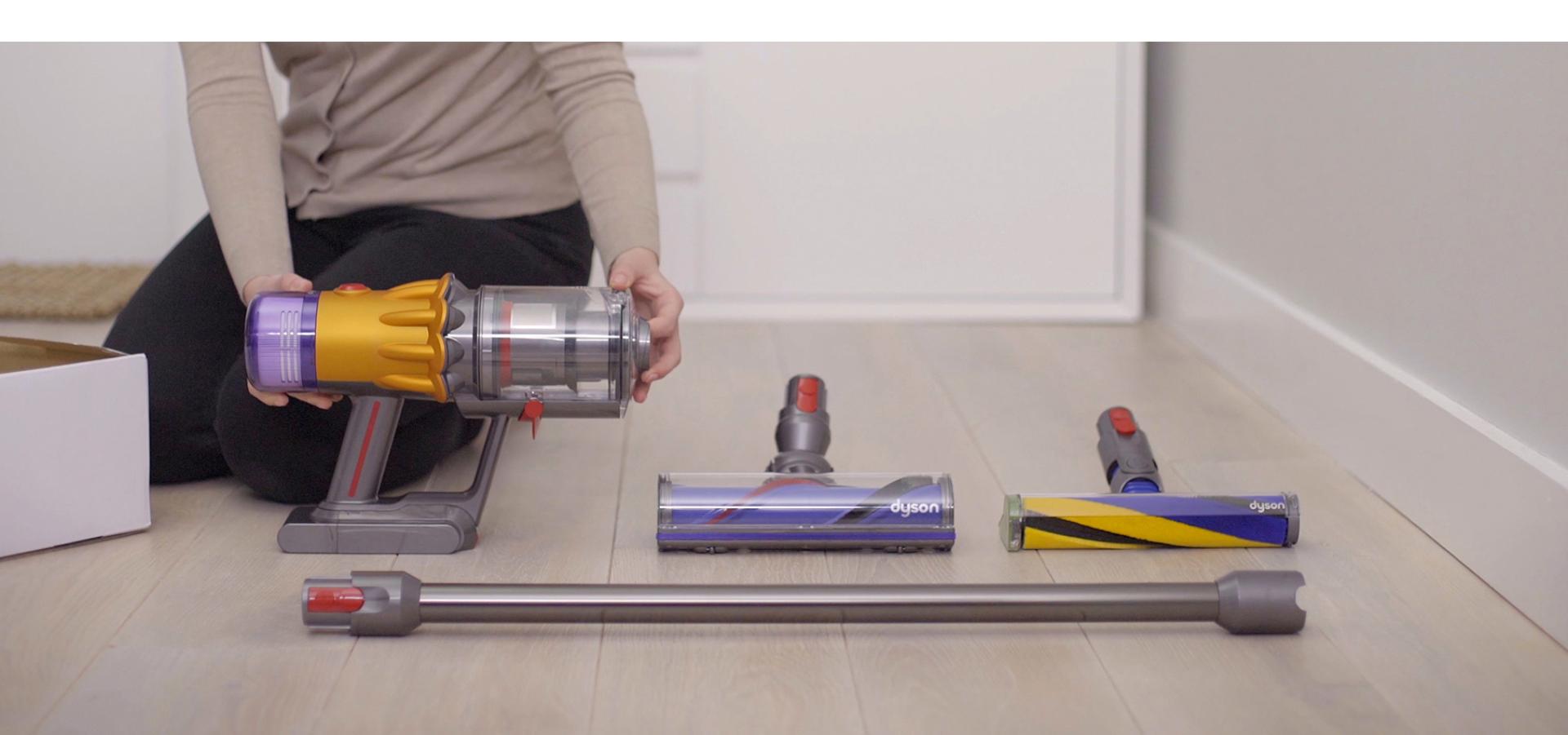 Someone holding the Dyson V12 Detect Slim vacuum while it's resting on the floor.