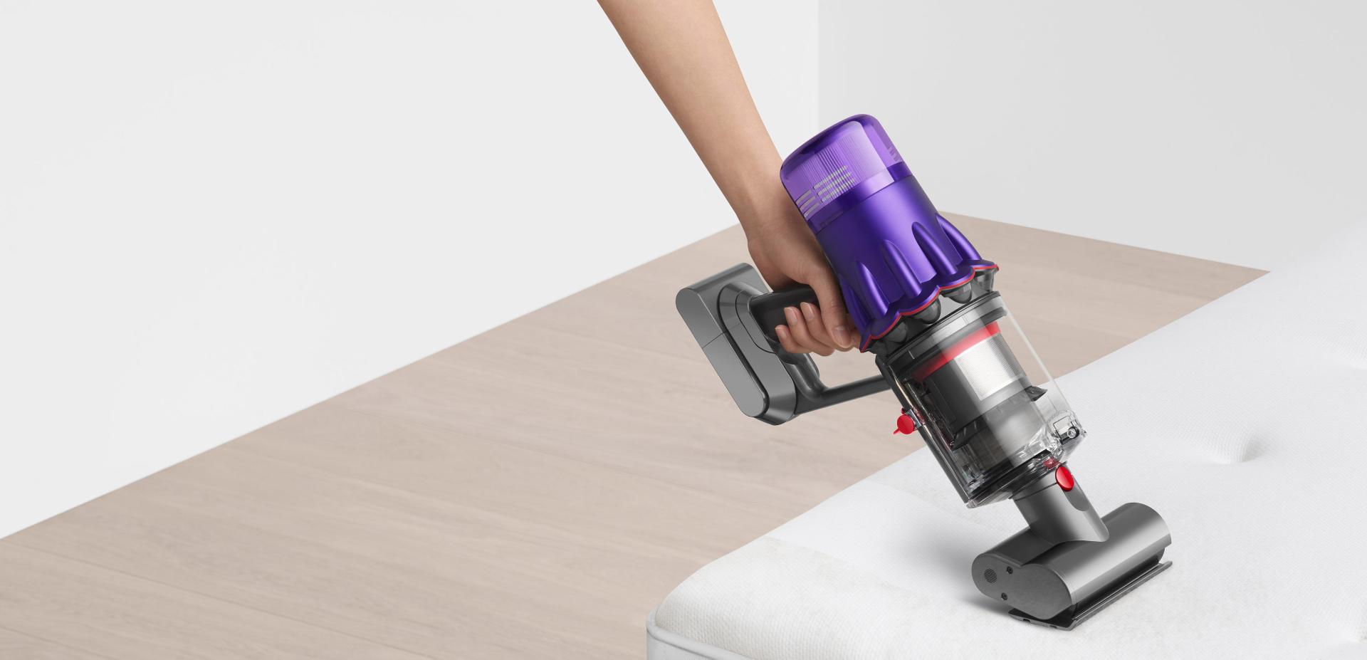 Dyson Digital Slim vacuum vacuuming a white sofa.