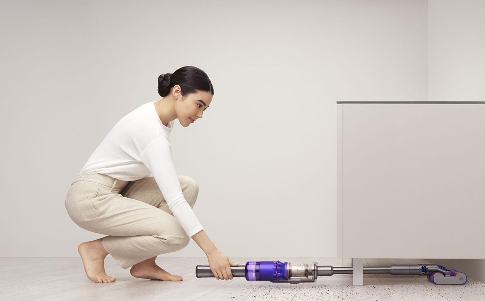 Dyson Omni-Glide vacuum vacuuming under a cabinet.