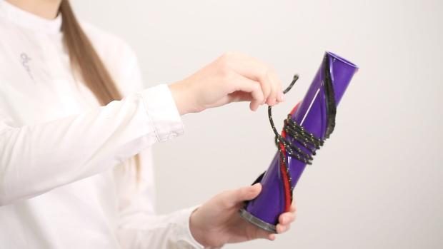 Osoba odwijająca zaplątany sznurek wokół wałka elektroszczotki