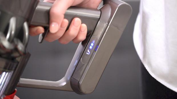 Ręka trzymająca odkurzacz, przybliżenie na diody na odkurzaczu