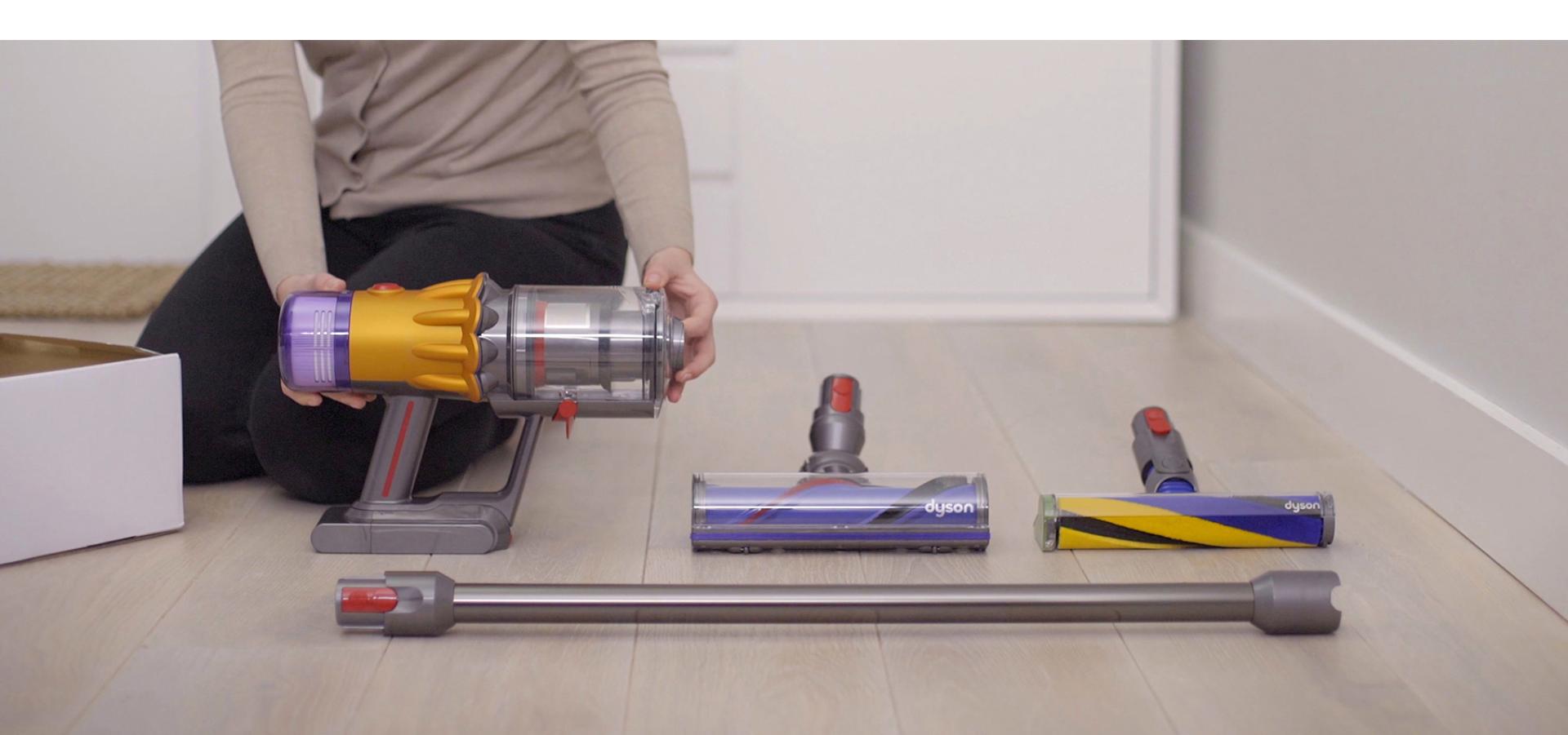Someone holding the Dyson V12 Slim vacuum while it's resting on the floor.