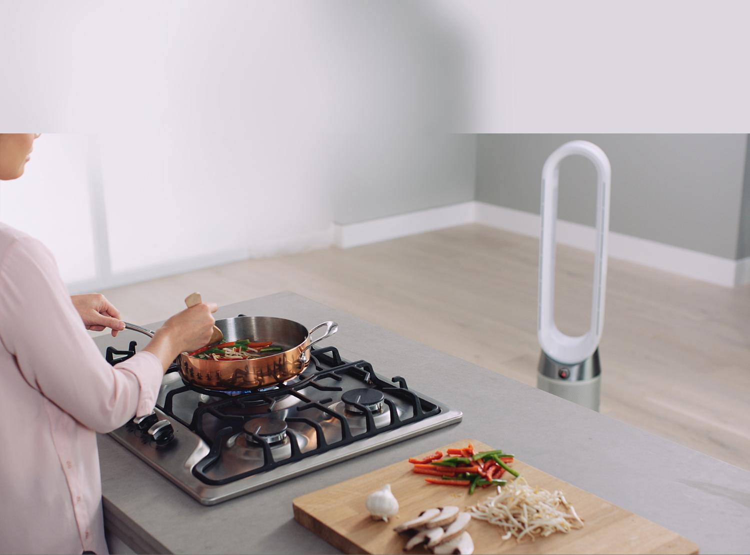Cooking food on a gas stove next to Dyson Pure Cool™ purifying fan