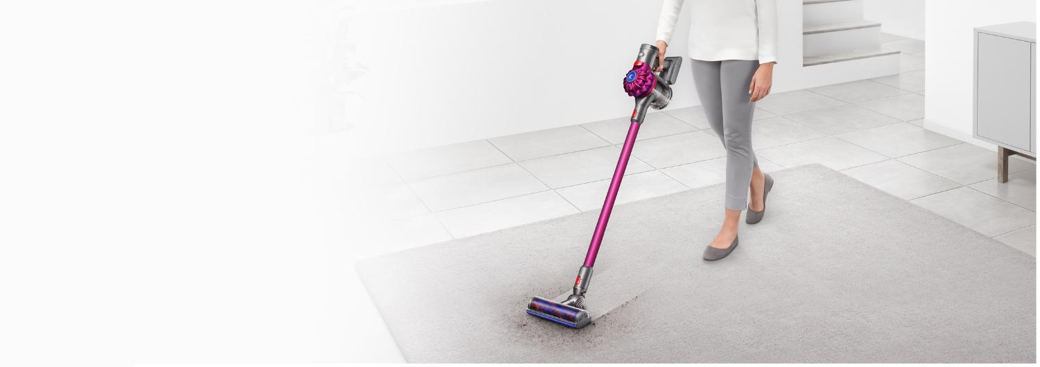 Modell verwendet einen Dyson V8, um einen cremefarbenen Teppich im Kinderzimmer zu reinigen.