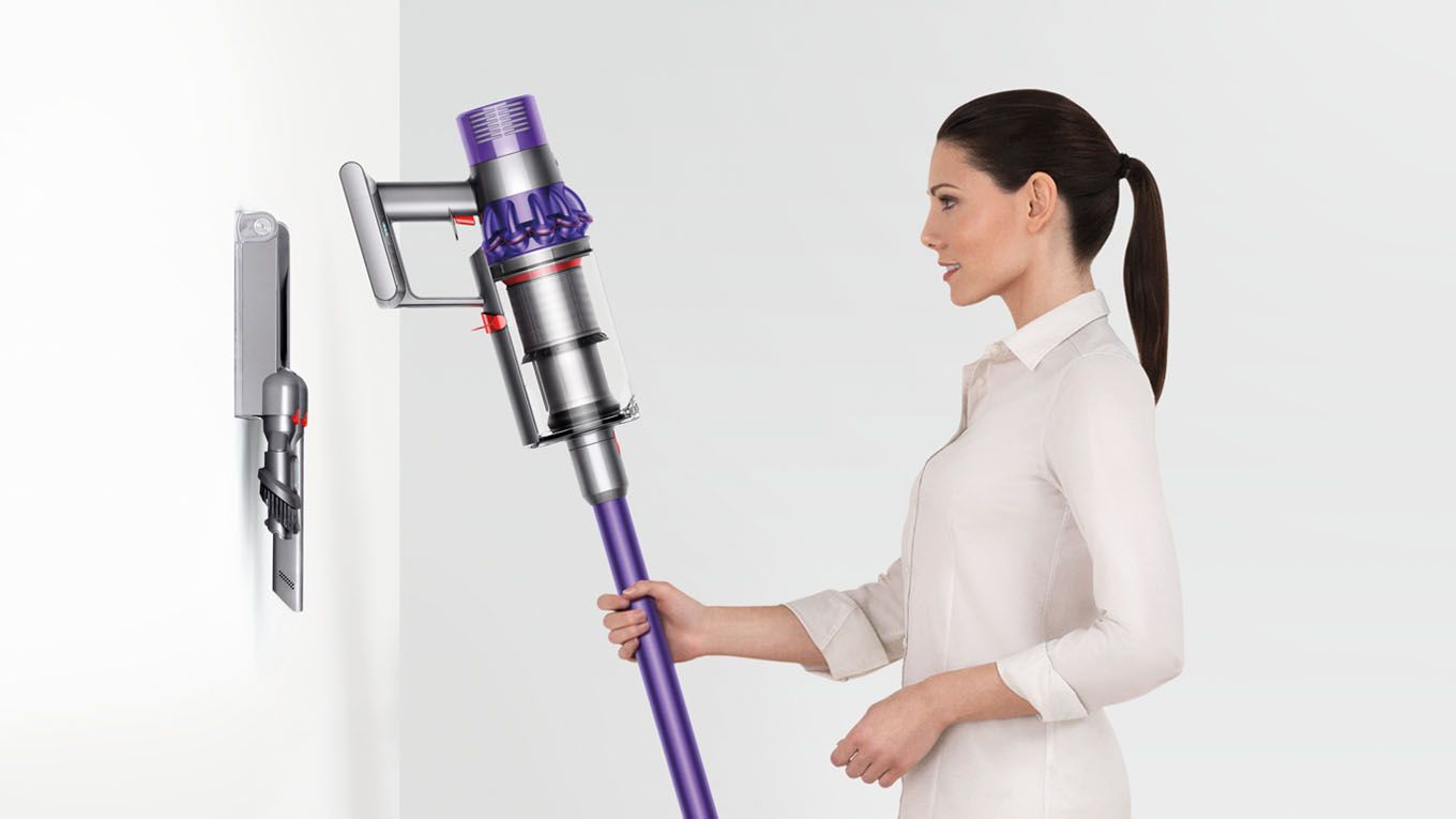 Woman placing Dyson V10 vacuum cleaner back onto docking station Woman placing Dyson V10 vacuum cleaner back onto docking station