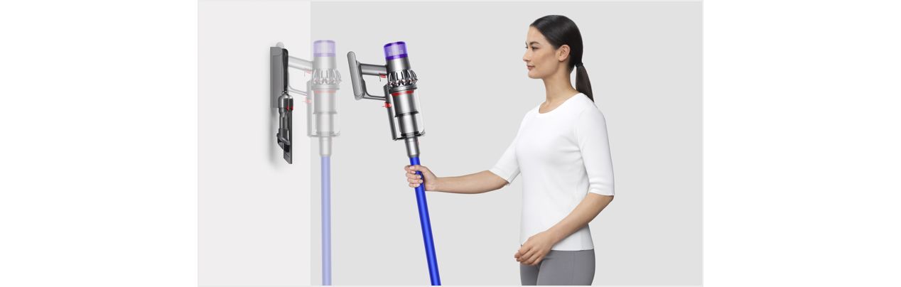 Woman placing Dyson V11 vacuum into wall charging dock