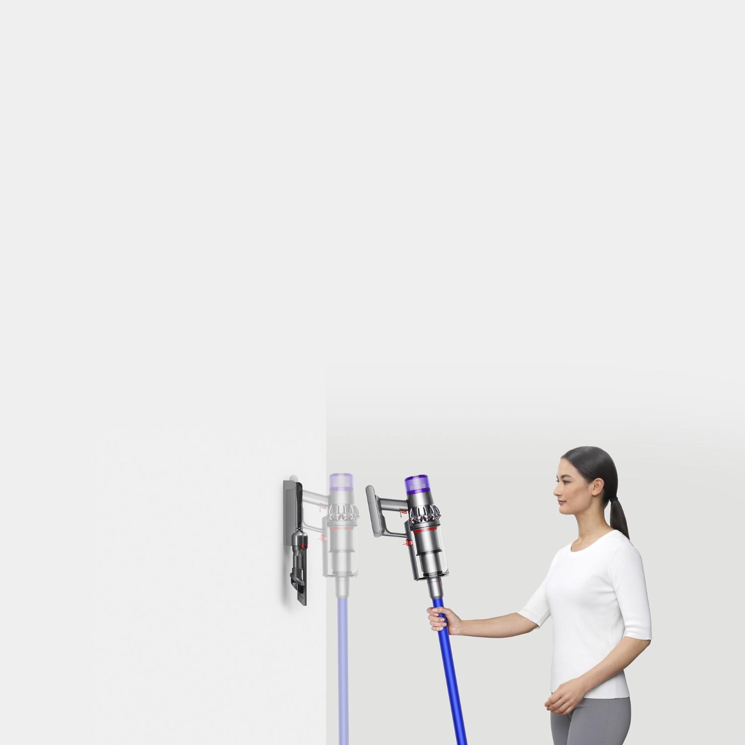 Woman placing Dyson V11™ vacuum into wall charging dock