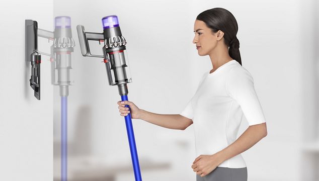 Woman placing Dyson V11™ vacuum into wall dock charging