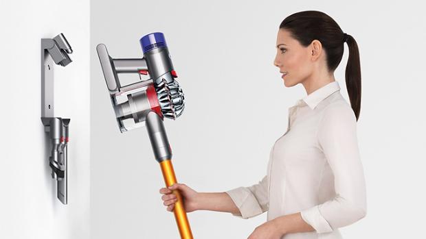 ผู้หญิงคนหนึ่งกำลังวางเครื่องดูดฝุ่นไร้สาย Dyson V8 ลงบนแท่นวางอย่างง่ายดาย