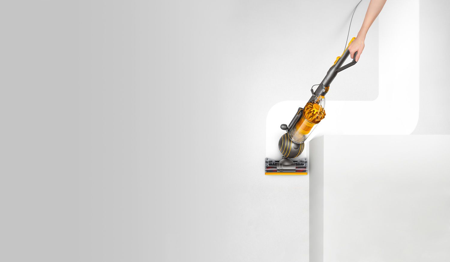 dyson-uprights-ball-multi floor-variant-next-up Dyson Ball Multi Floor 2 vacuum cleaner rounding a corner of sofa as it picks up dirt