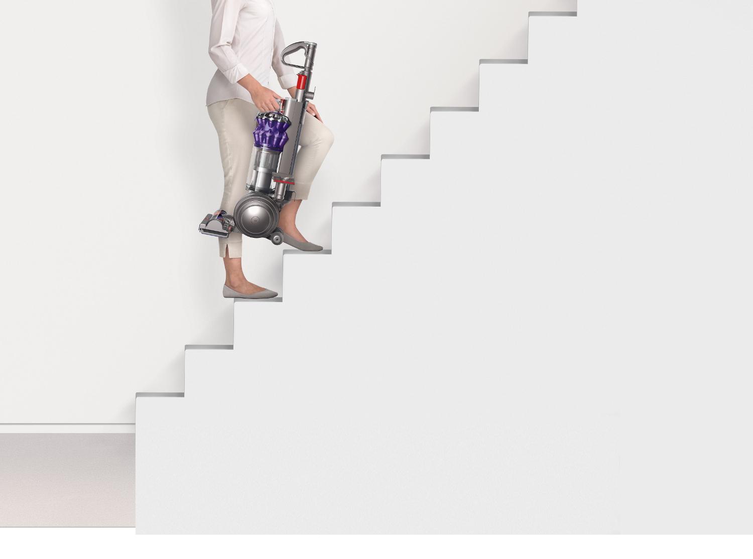 Woman walking up stairs with the Dyson Small Ball™ vacuum cleaner