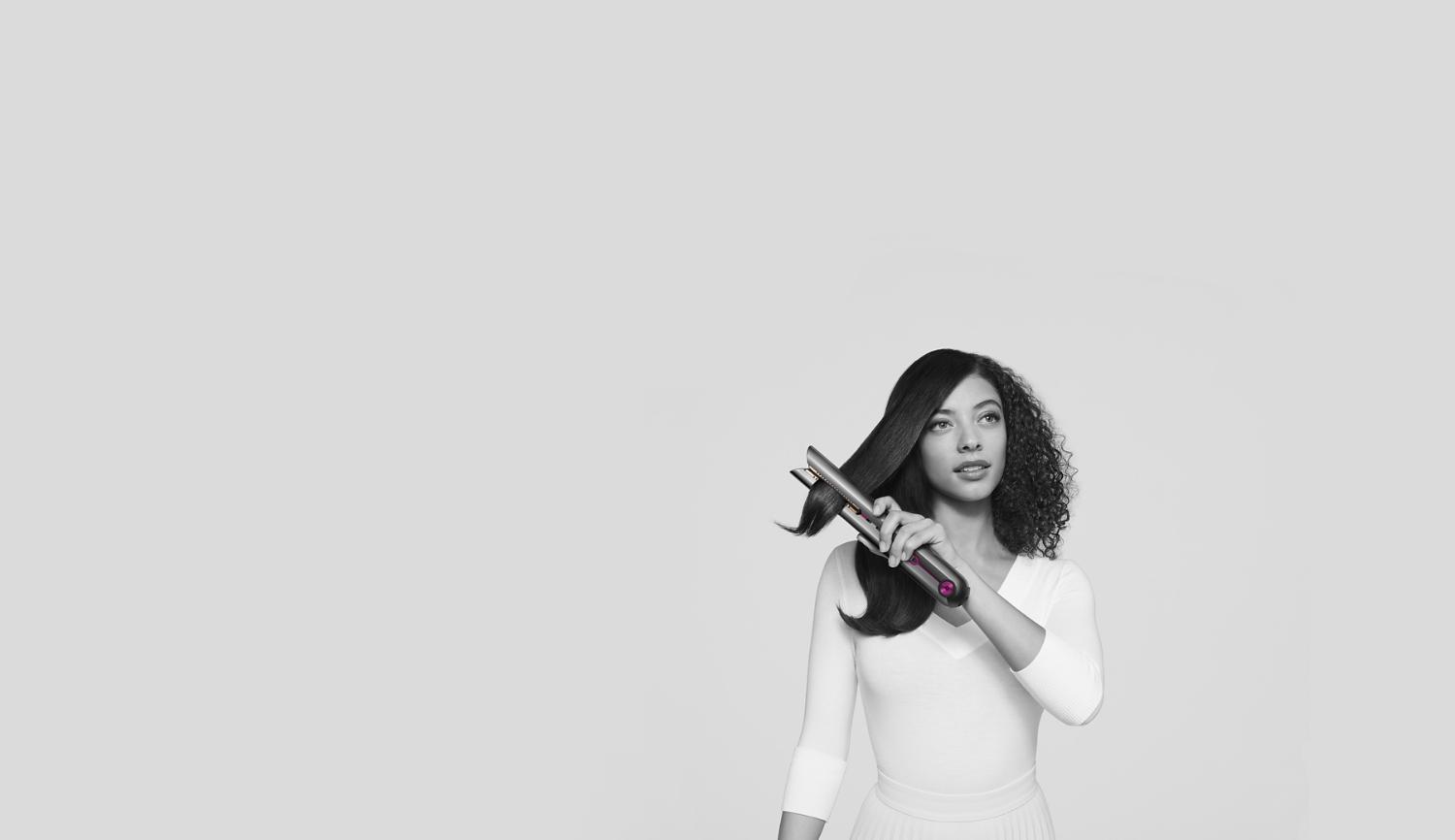 Woman achieving beautifully straight hair with the Dyson Corrale straightener