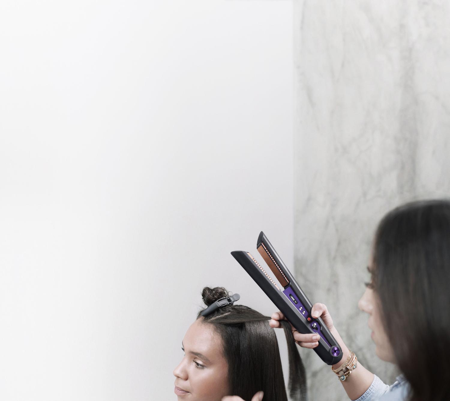 Close up of professional stylist using the Dyson Corrale hair straightener