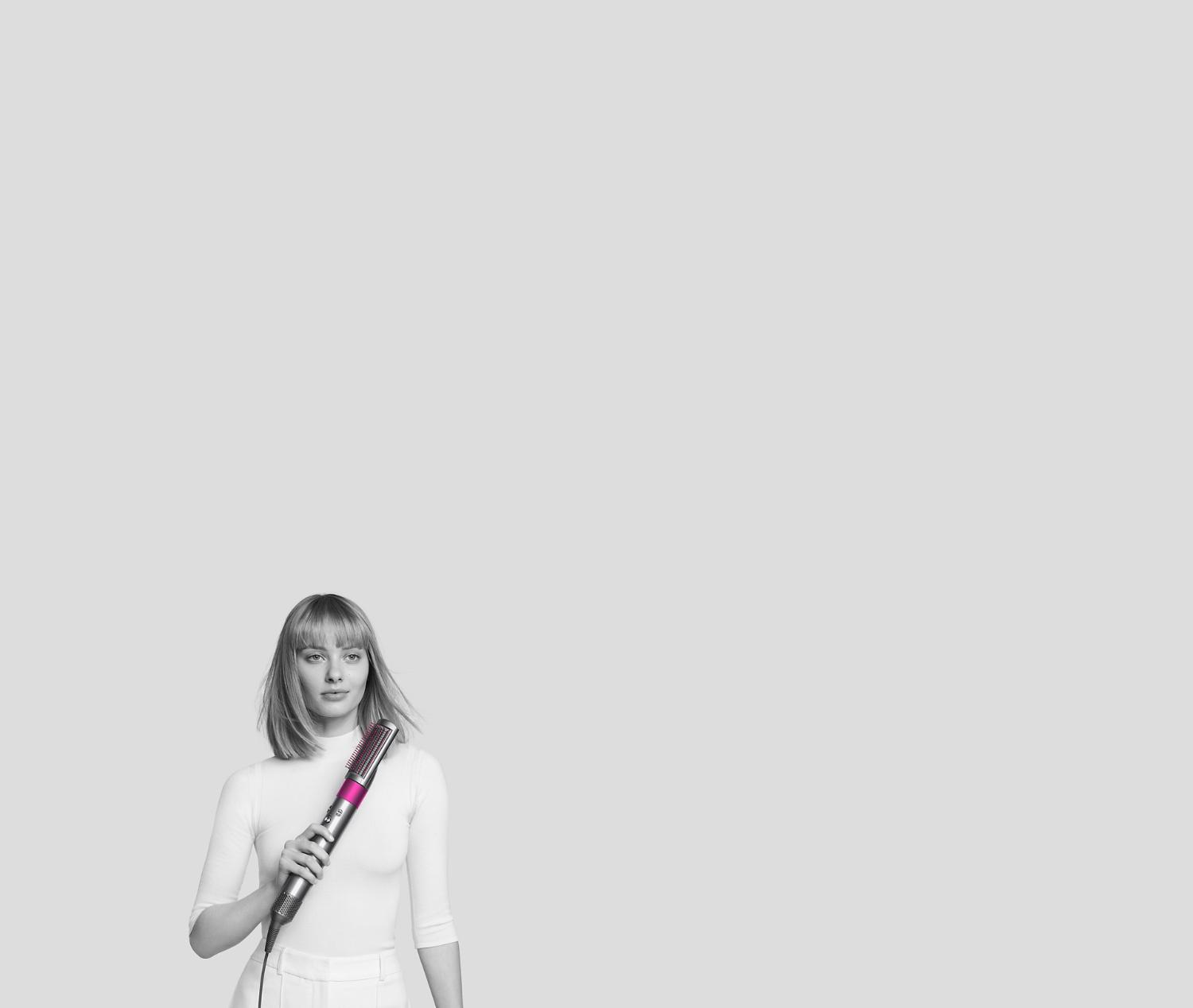 Donna che si arriccia i capelli con lo styler Dyson Airwrap.
