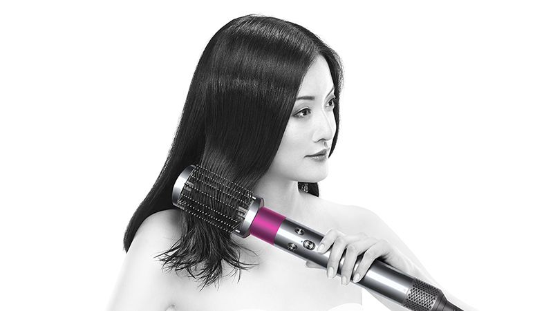 Model using The Dyson Airwrap™ to smooth frizzy hair Model using The Dyson Airwrap™ to smooth frizzy hair