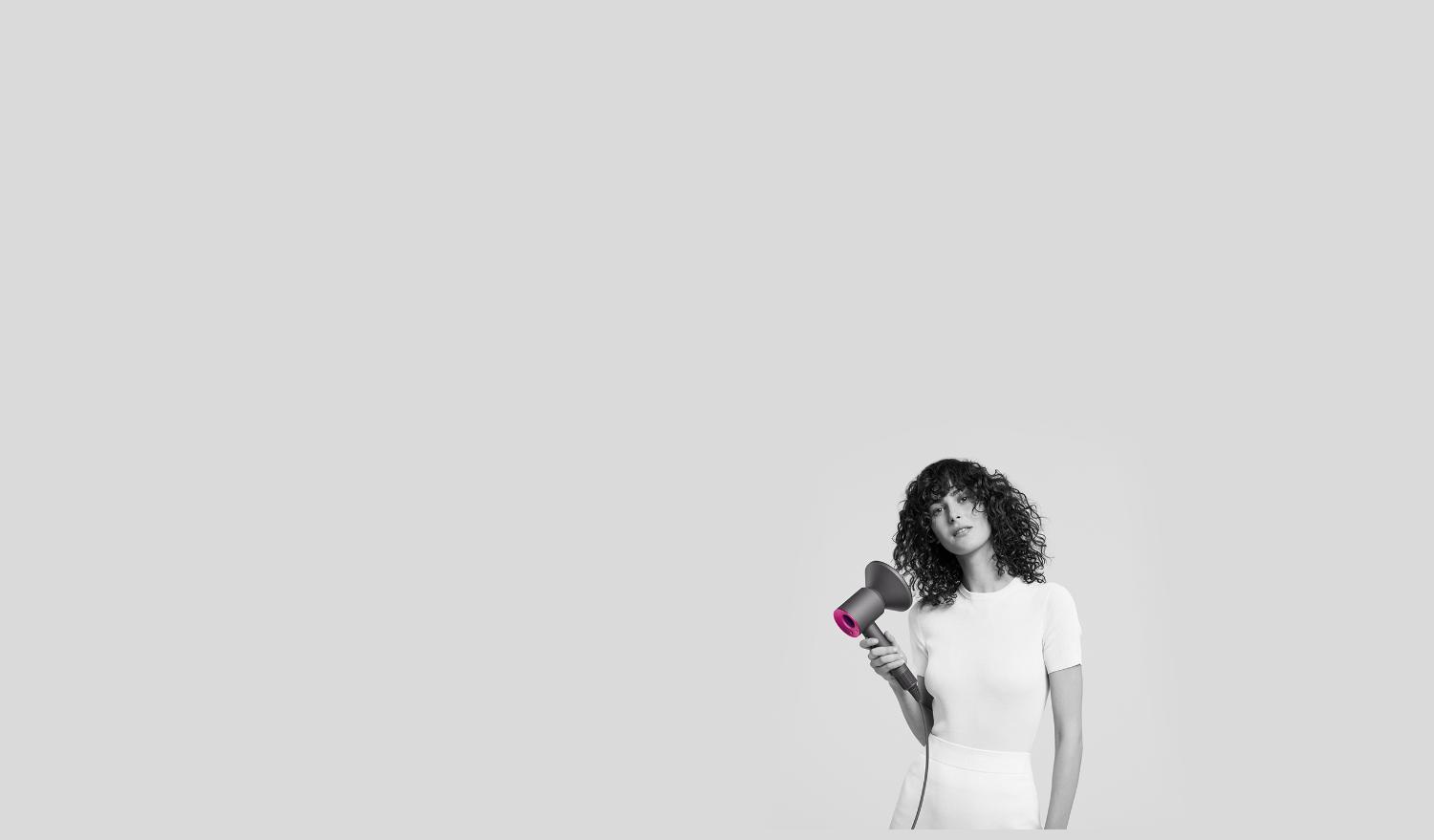 Woman using Dyson Supersonic with Diffuser attachment