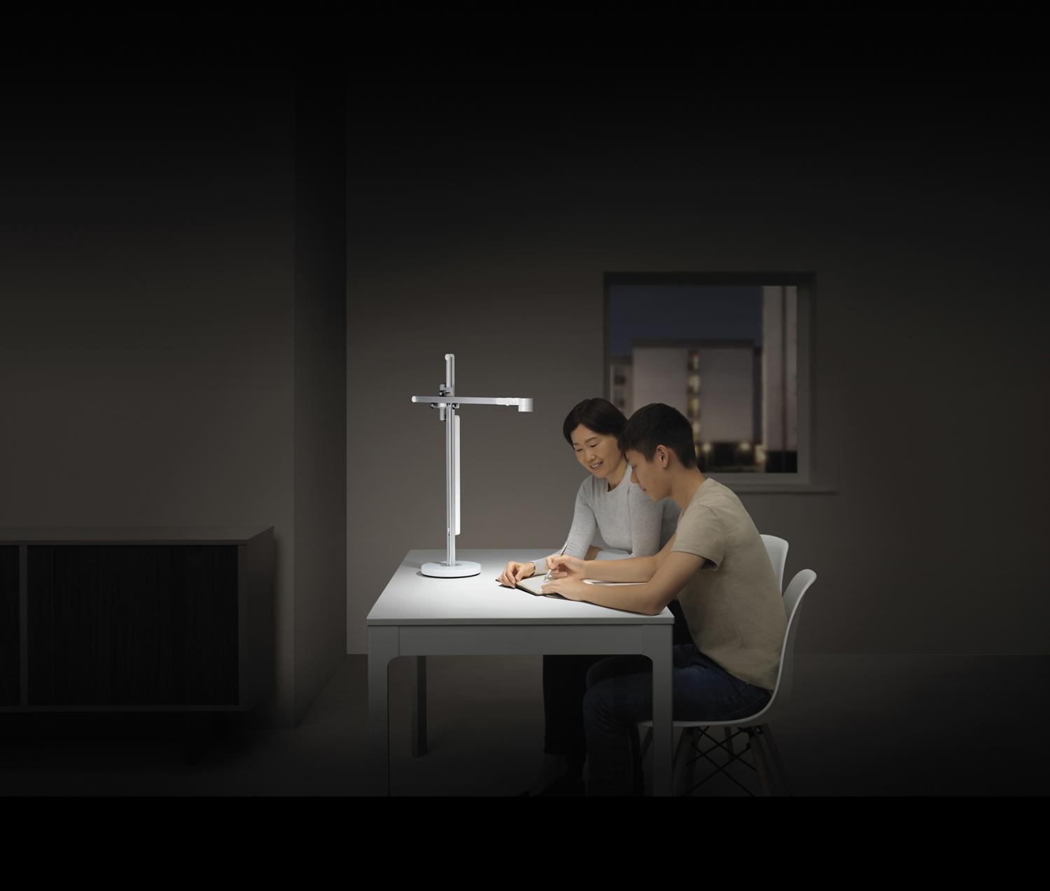 Teenager studies with his mother in powerful desk light