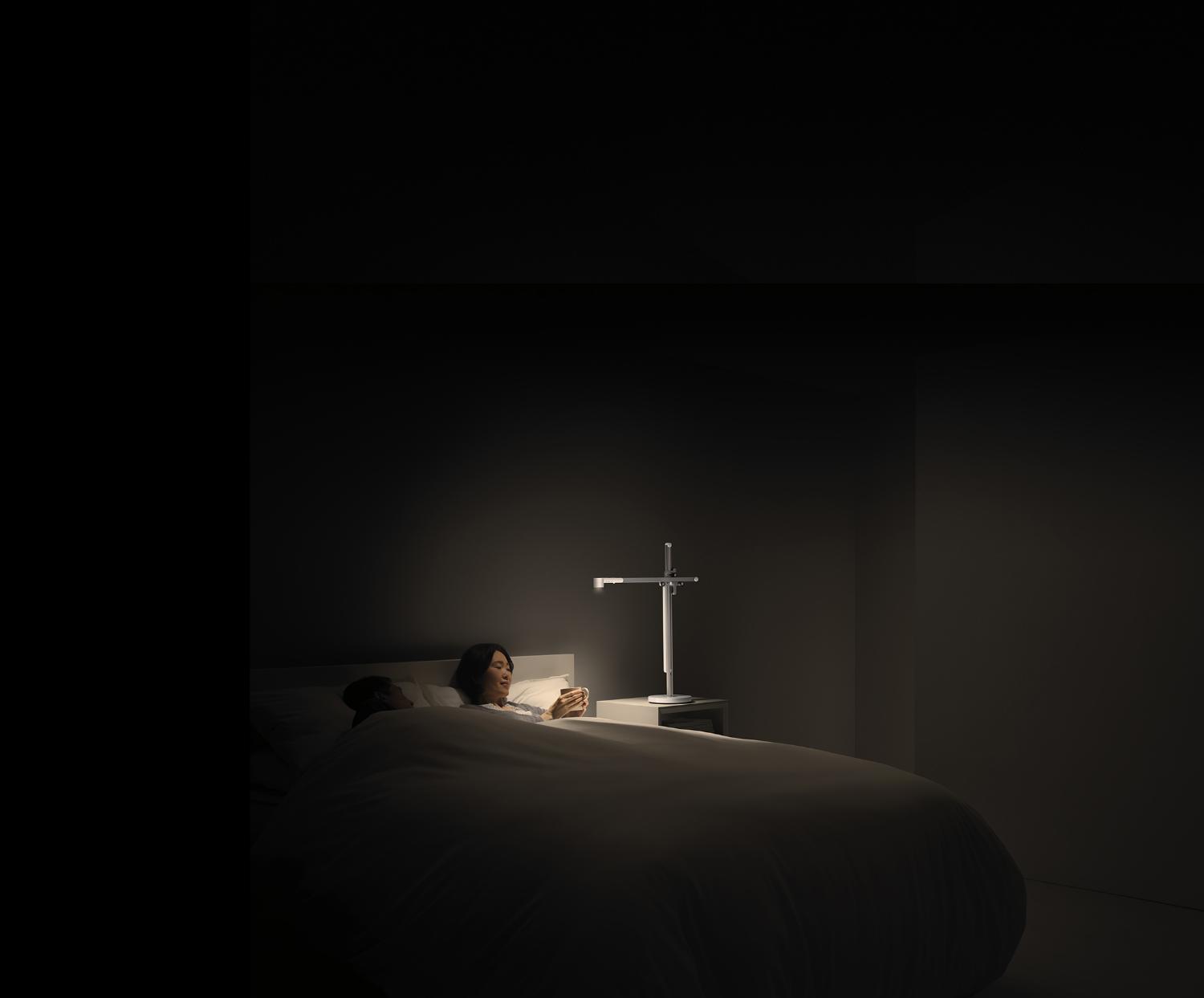 A woman drinks tea in bed in relaxing light