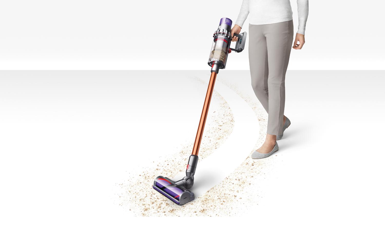 Personne en train de nettoyer une moquette grise dans un salon à l’aide de l’aspirateur Dyson V10.