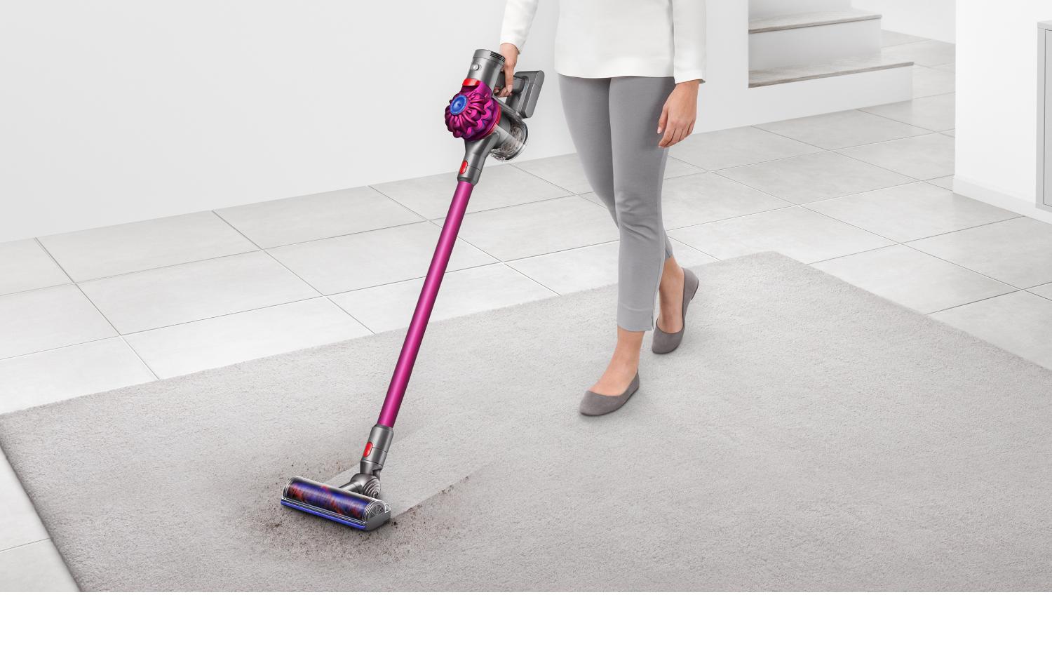 Personne en train de nettoyer une moquette grise à l’aide de l’aspirateur Dyson V7.