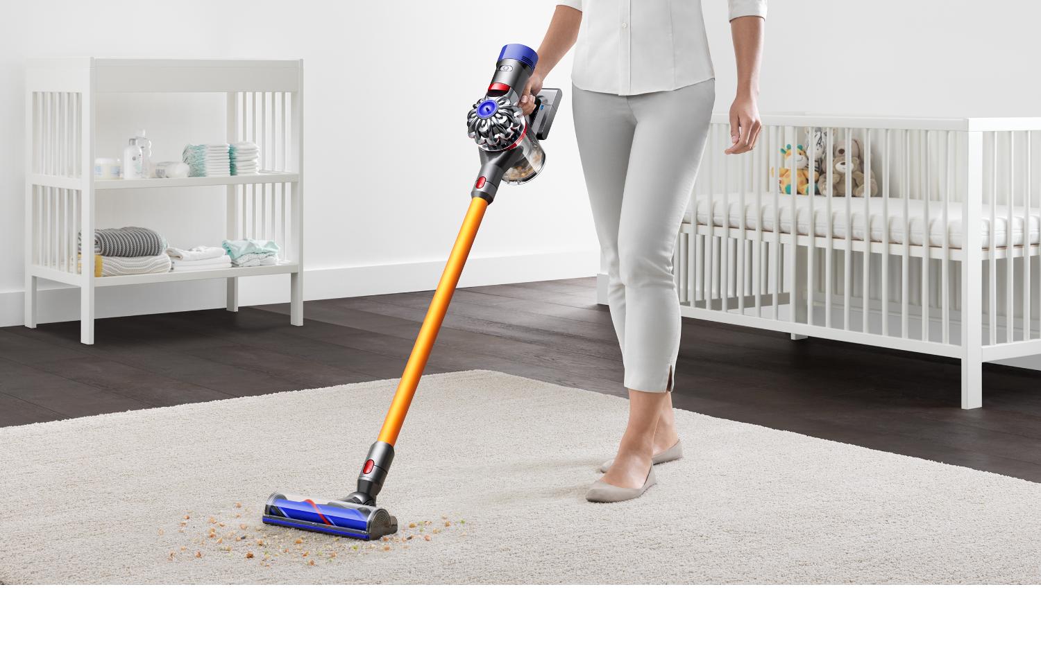 Personne en train de nettoyer une moquette blanc crème dans une chambre de bébé à l’aide de l’aspirateur Dyson V8.