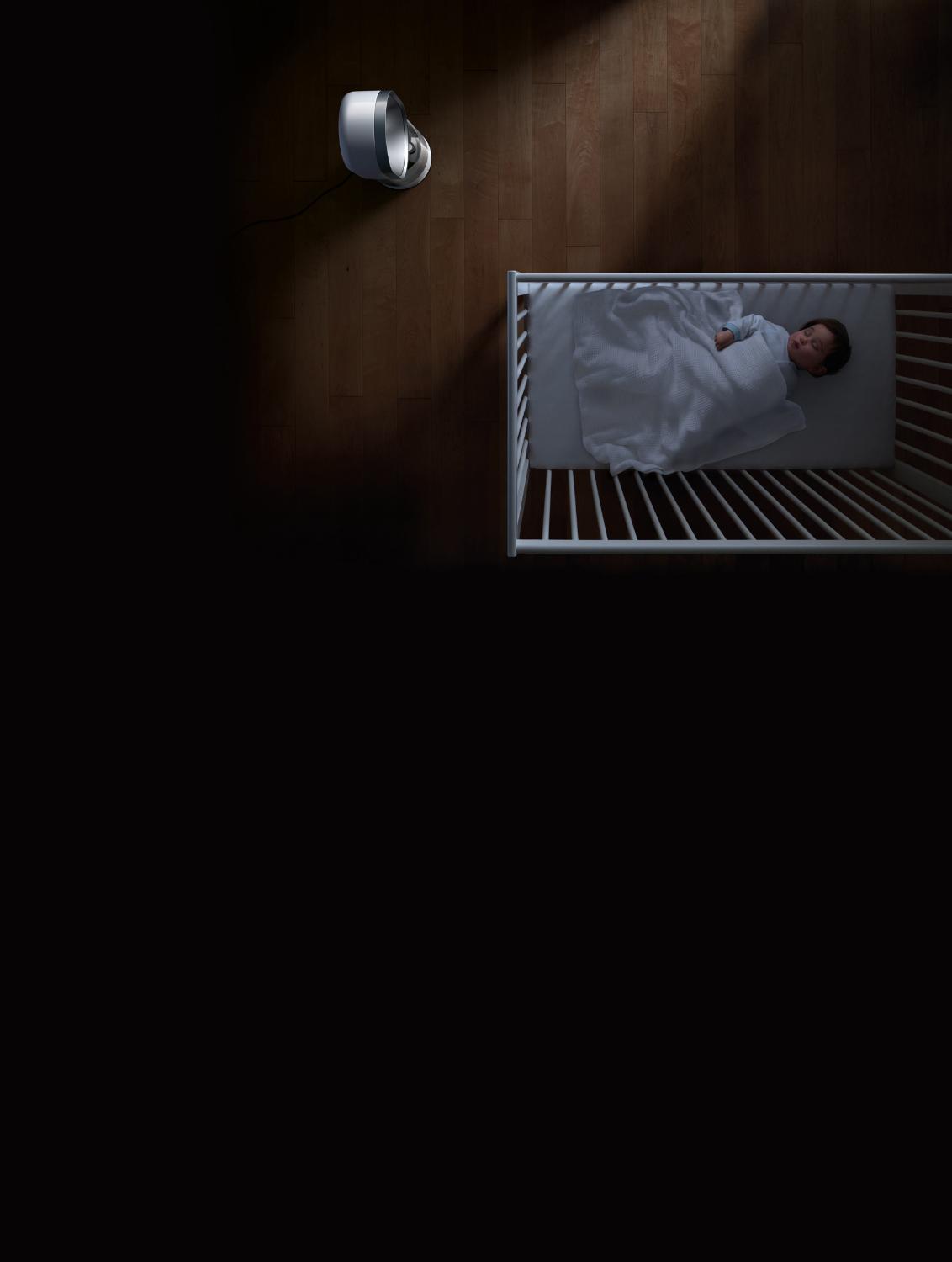 Baby sleeping in a cot beside purifier