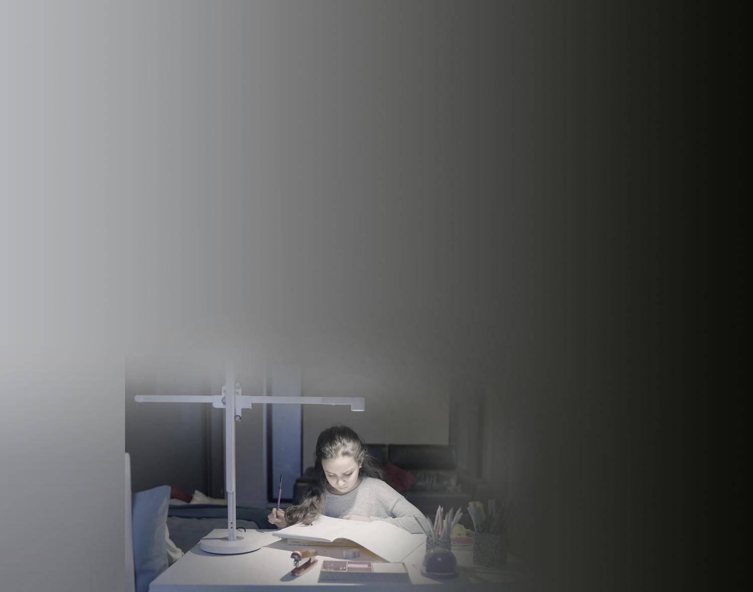 Teenager studies with his mother in powerful desk light