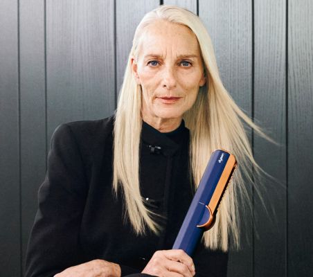 Une photo d'une femme aux longs cheveux blonds, tenant le Lisseur Séchant Dyson Airstrait™