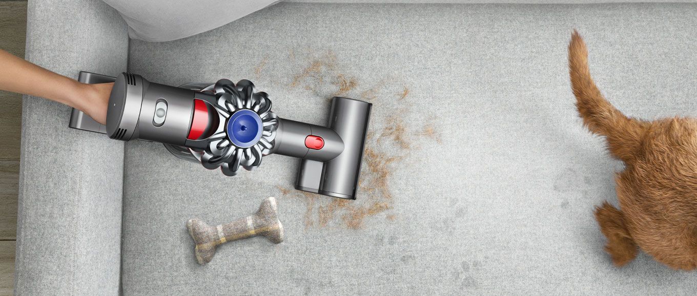 Dyson in handheld mode picking up pet hair from a sofa
