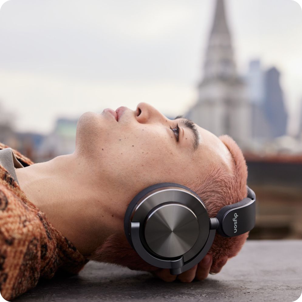 A person wearing Dyson headphones with a cityscape in the background.