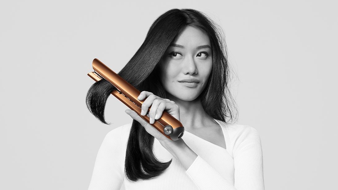 Modèle se coiffant avec un lisseur Dyson Corrale cuivré