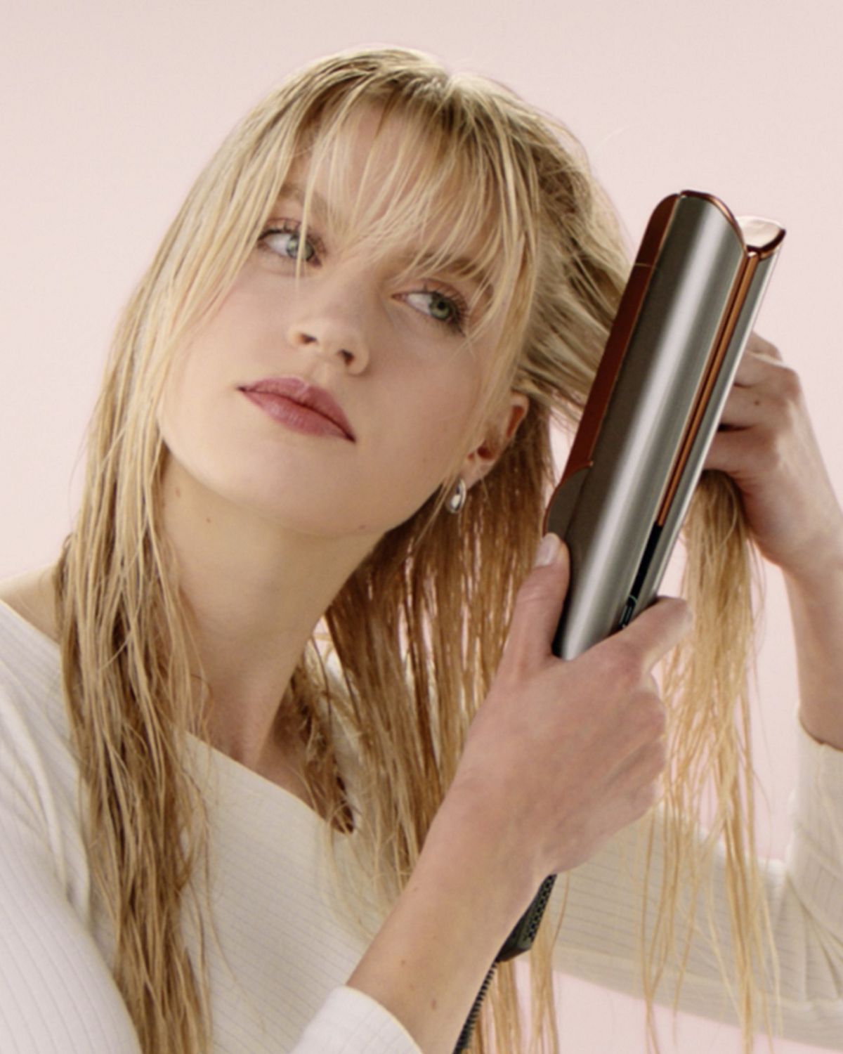A blonde model uses the Root drying mode on the Dyson Airstrait to add volume to her hair.