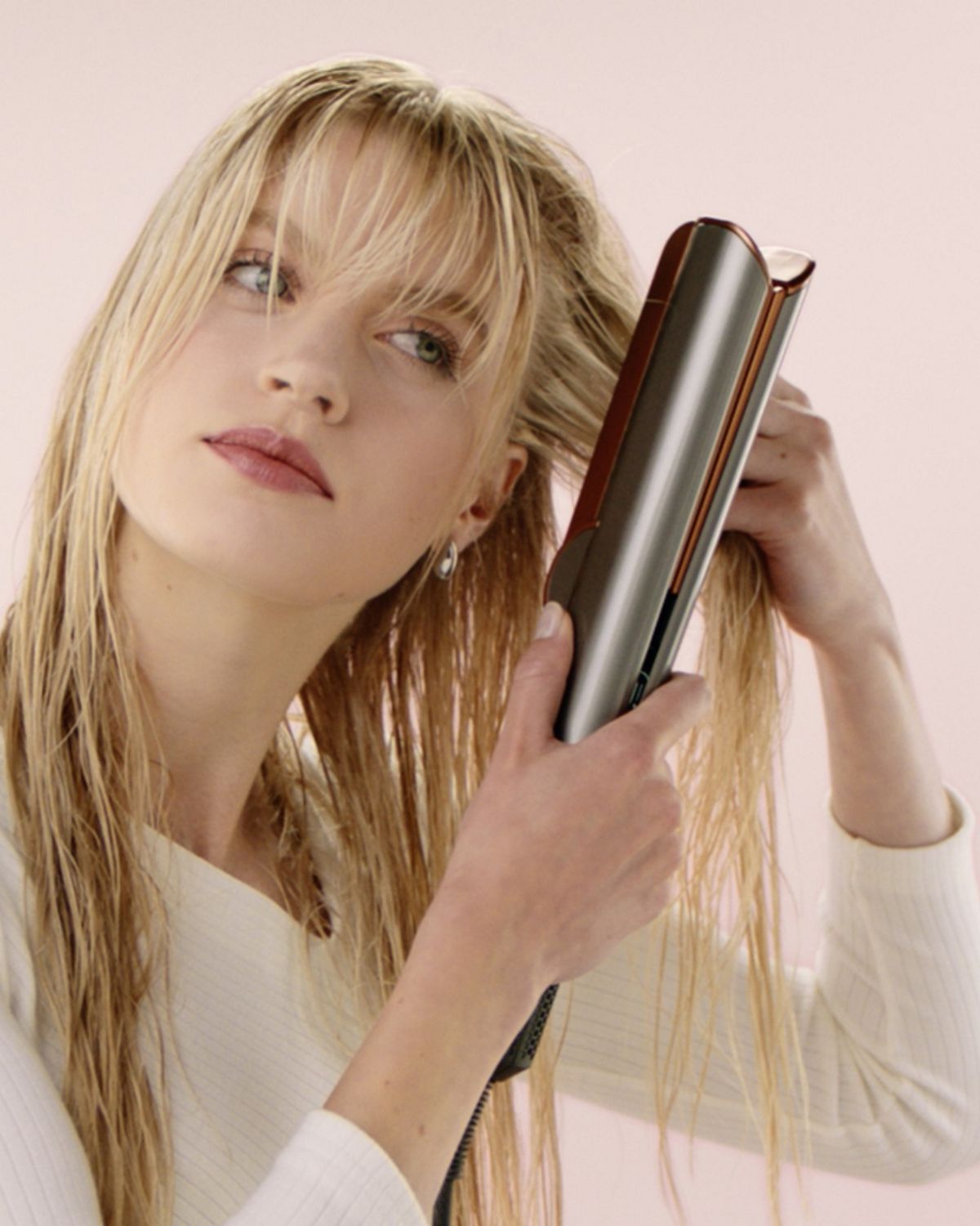 A blonde model uses the Root drying mode on the Dyson Airstrait to add volume to her hair.