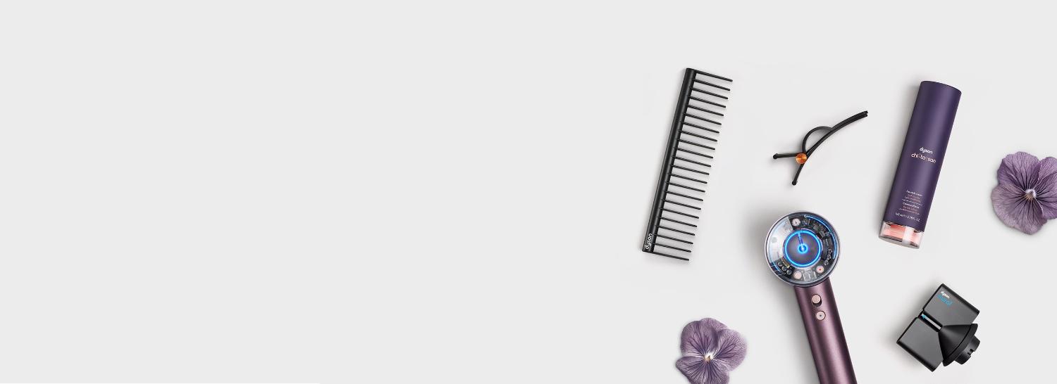 The Dyson Supersonic Nural hair dryer in Jasper plum surrounded by attachments and accessories.