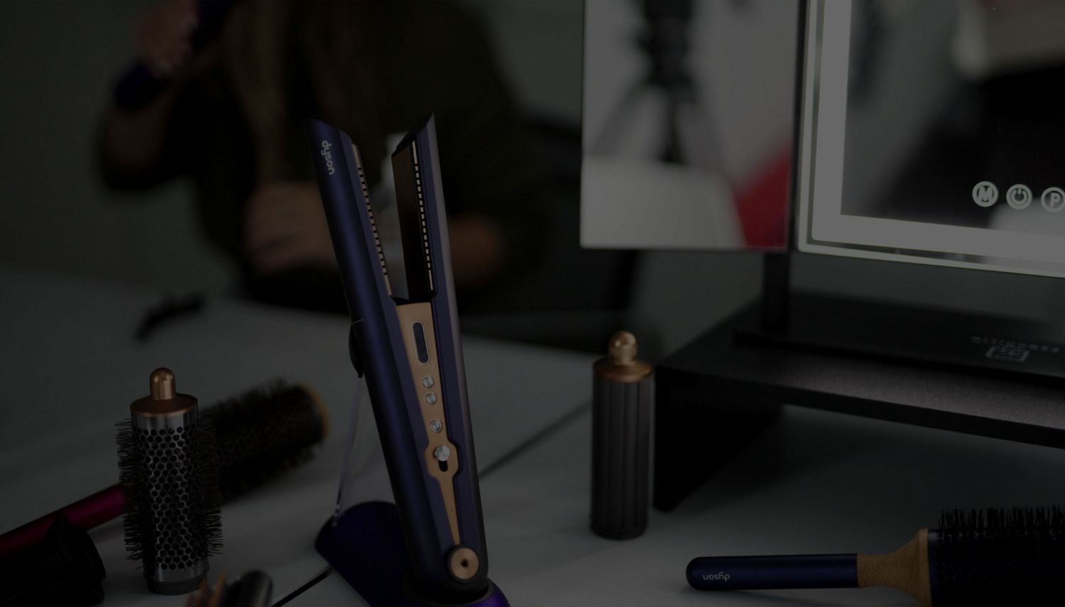 Un mannequin et des coiffeurs utilisant l’embout de finition lisse du sèche-cheveux Dyson Supersonic pour créer une queue de cheval basse