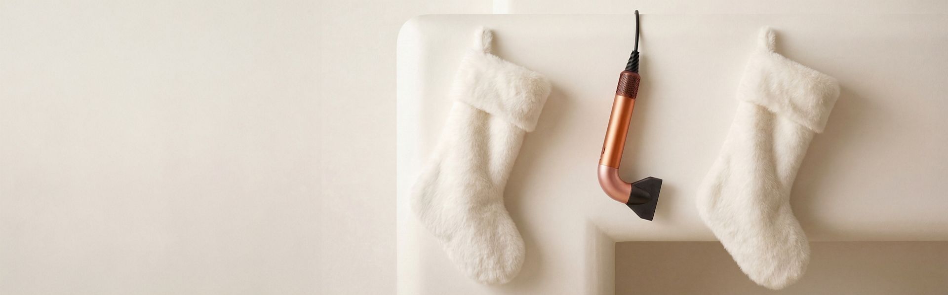 The Dyson Supersonic r hair dryer hanging in a line between a pair of Christmas stockings.