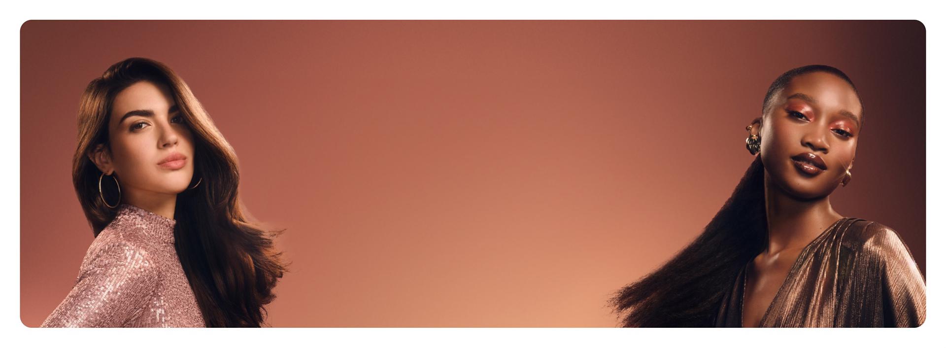 A pair of models with luxurious, healthy hair styled with Dyson products and devices.