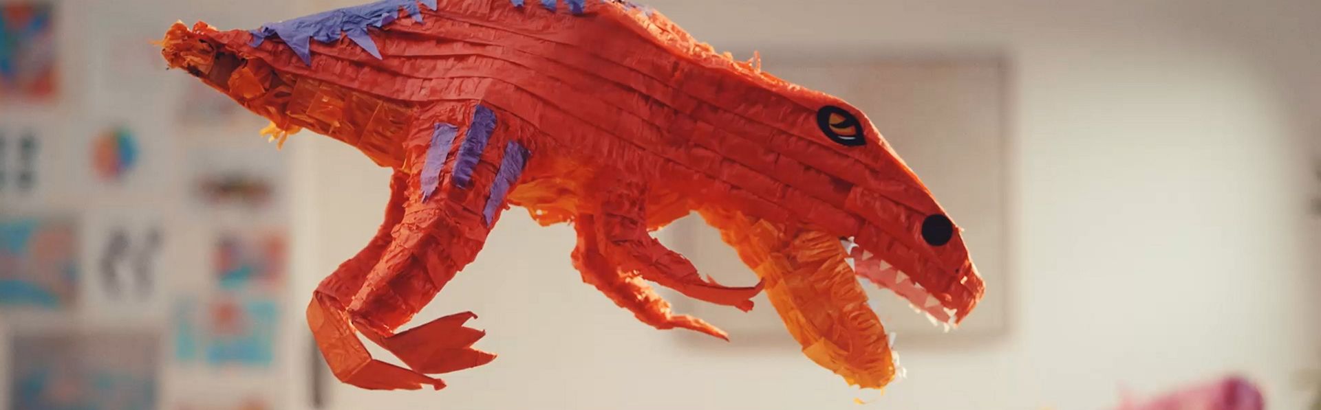 Confetti and sweets rain down from a dinosaur pinata as a mother retrieves a Dyson cordless vacuum from its Wall Dok.